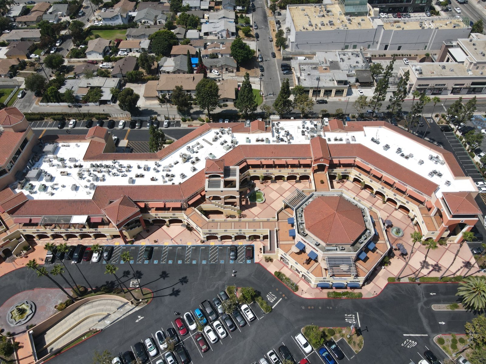 Aerial view of a restored commercial shopping center with white-coated flat roofs