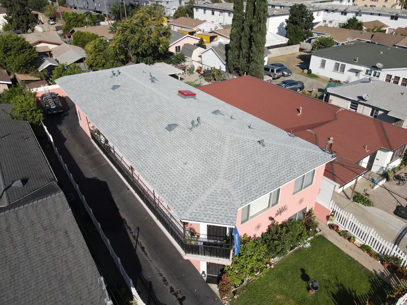 Aerial view of a grey asphalt shingle roof on a pink home