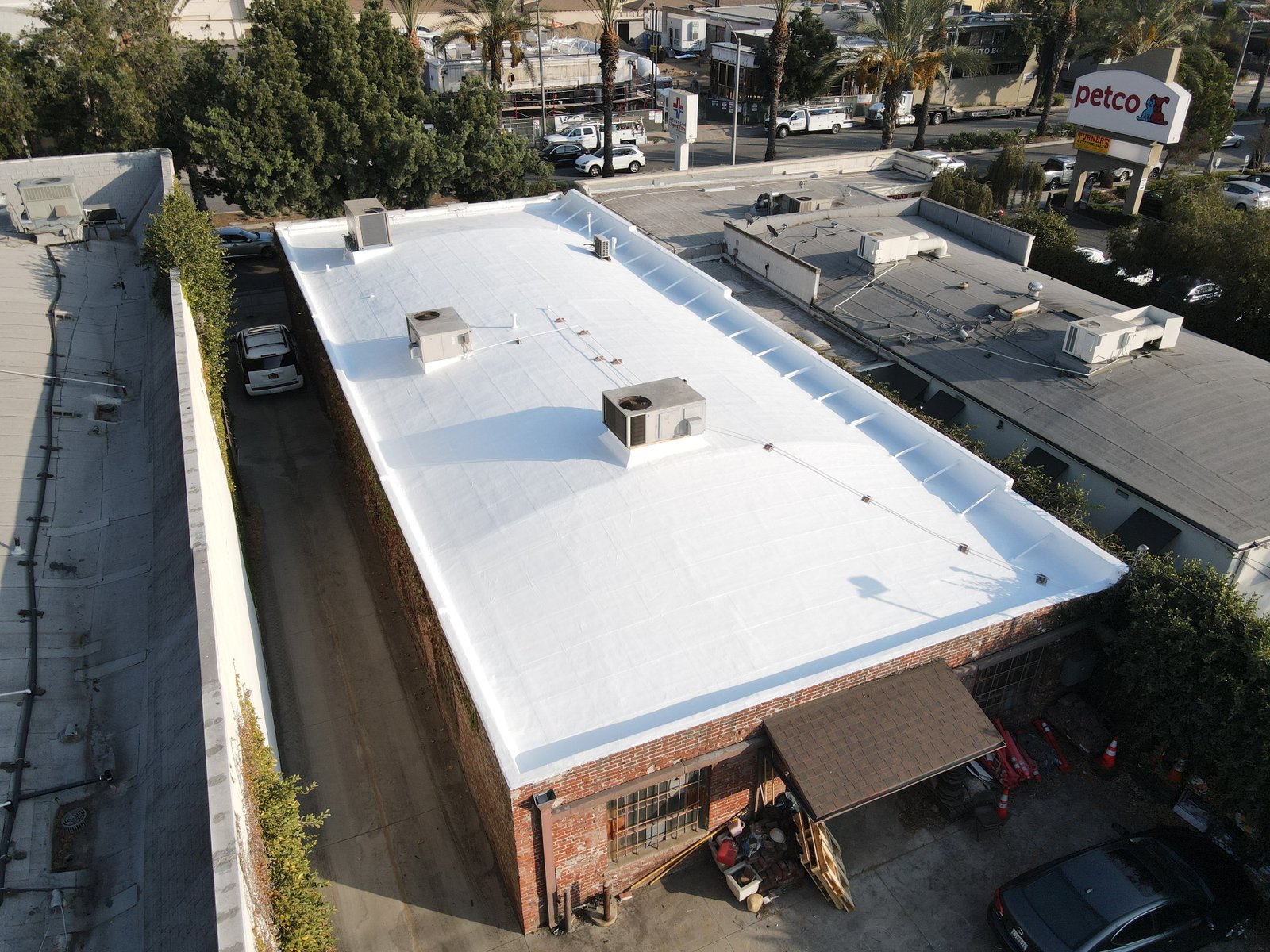 Aerial view of a commercial building with a freshly restored white fluid-applied roof