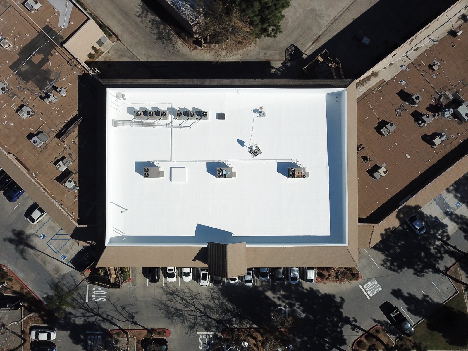 Aerial view of a commercial building with a freshly restored white fluid-applied roof